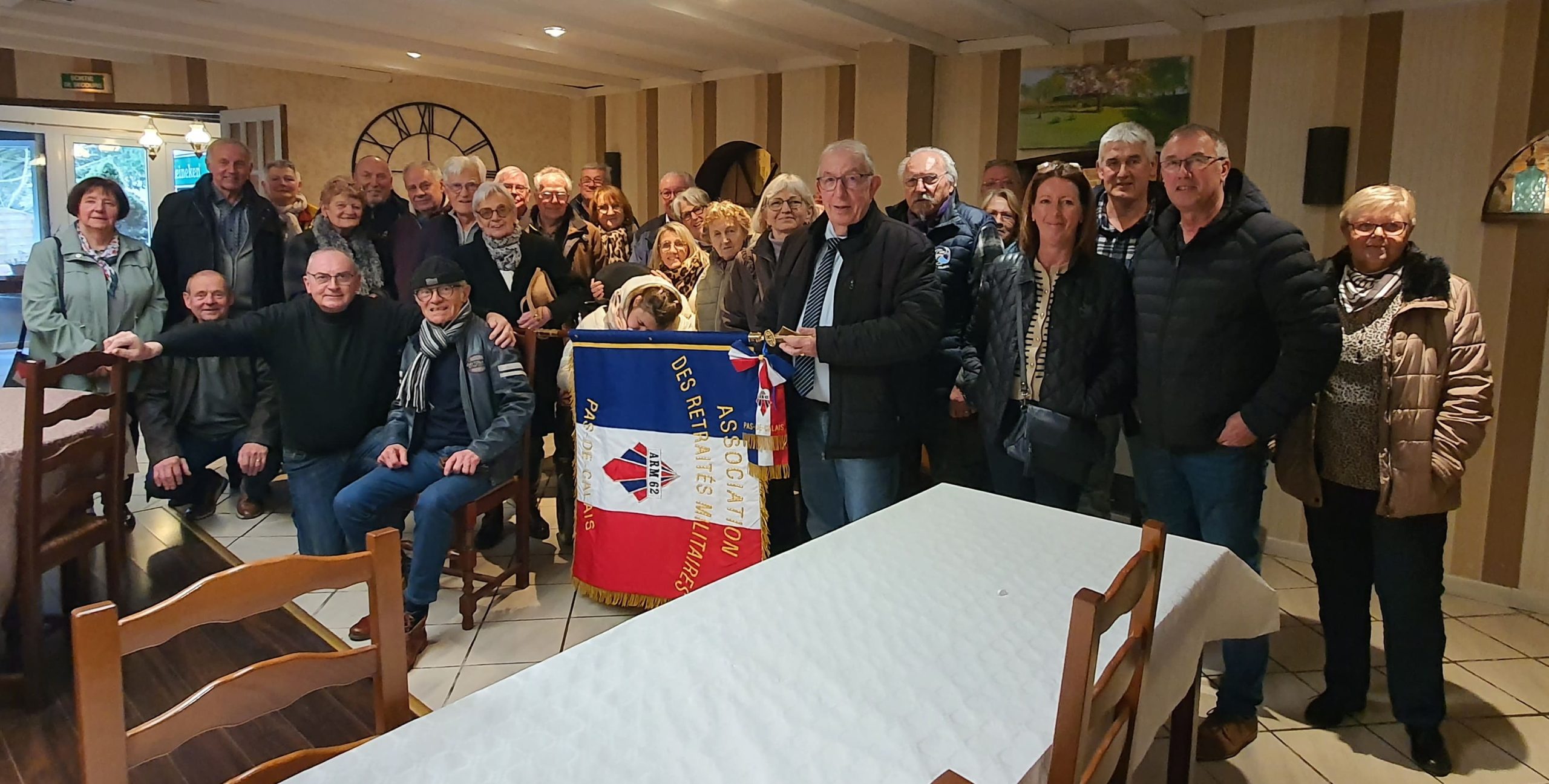 Photo de groupe de tous les adhérents de l'ARM62 lors de l'AG 2026 avec le drapeau de l'association au centre